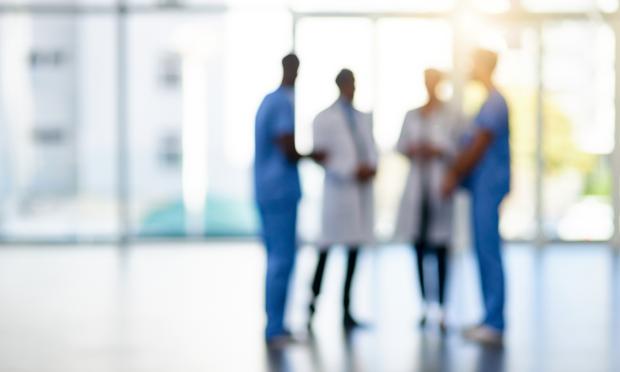A blurred picture of medical professionals talking to each other in a lobby.